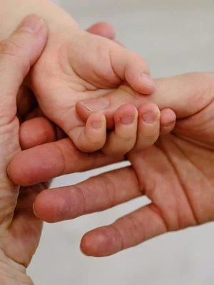 Mutter massiert ihrem Kind die Hand und sorgt damit für angenehme Berührungen.