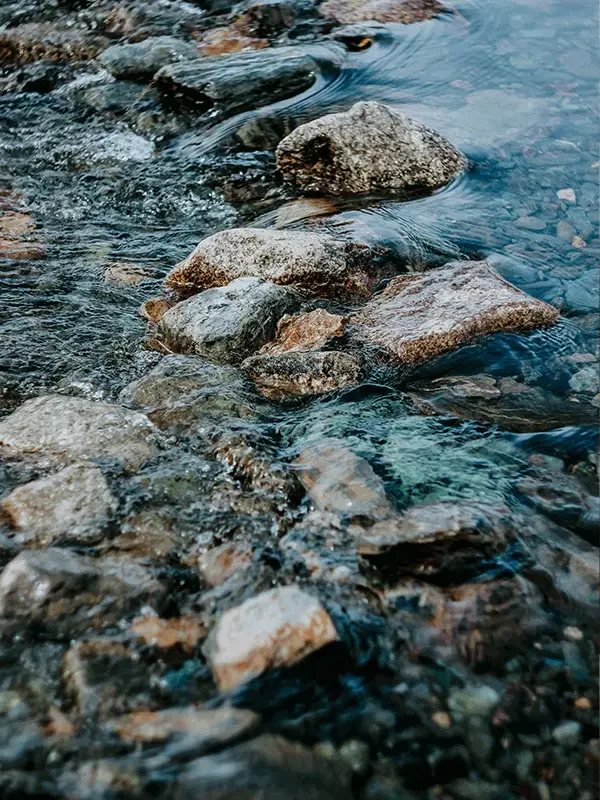 Ein fließender Bach schlängelt sich über Steine hinweg – ein perfektes Symbol für das Prinzip „Panta Rhei“. Wie das Wasser, das stetig in Bewegung bleibt, verändert sich auch das Leben ständig und findet immer neue Wege.